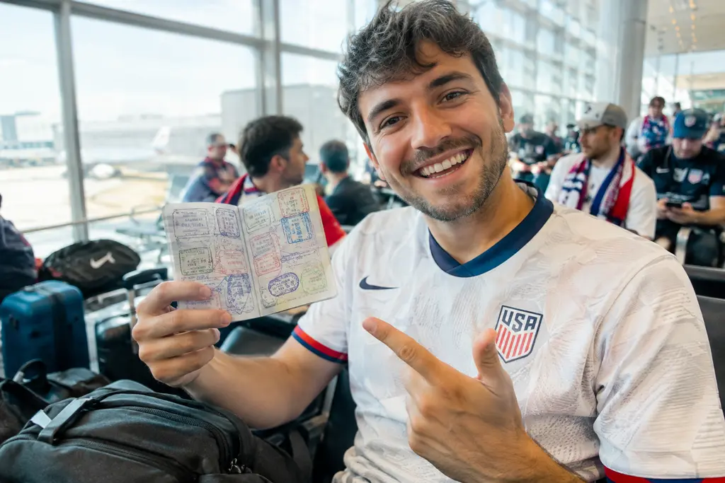 USMNT Travel Planning scene with supporters outside a soccer stadium before a night match